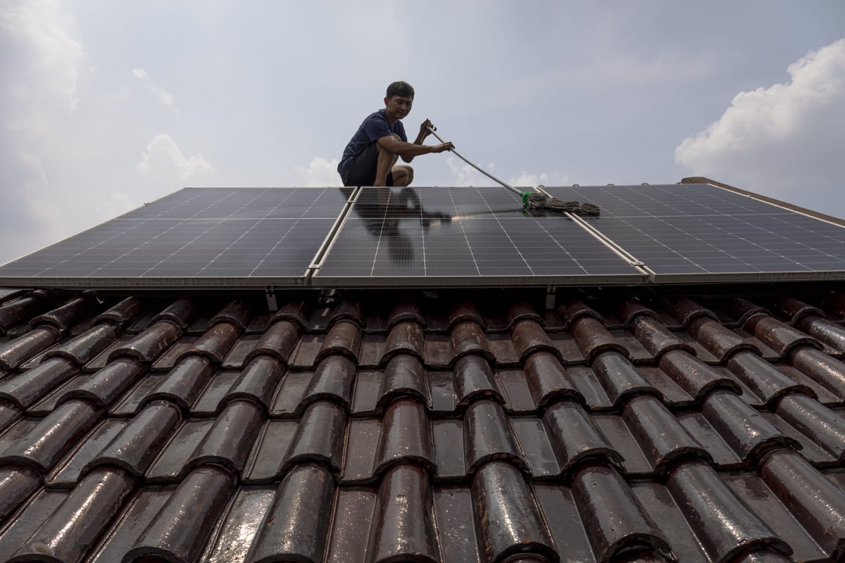 Climate and energy campaigner Hadi Priyanto cleaning solar panels on his home in Depok City, West Java, Indonesia, 17 November 2023 (Aji Styawan/Climate Visuals, CC BY-NC-ND 4.0 - main image also courtesy the same website)