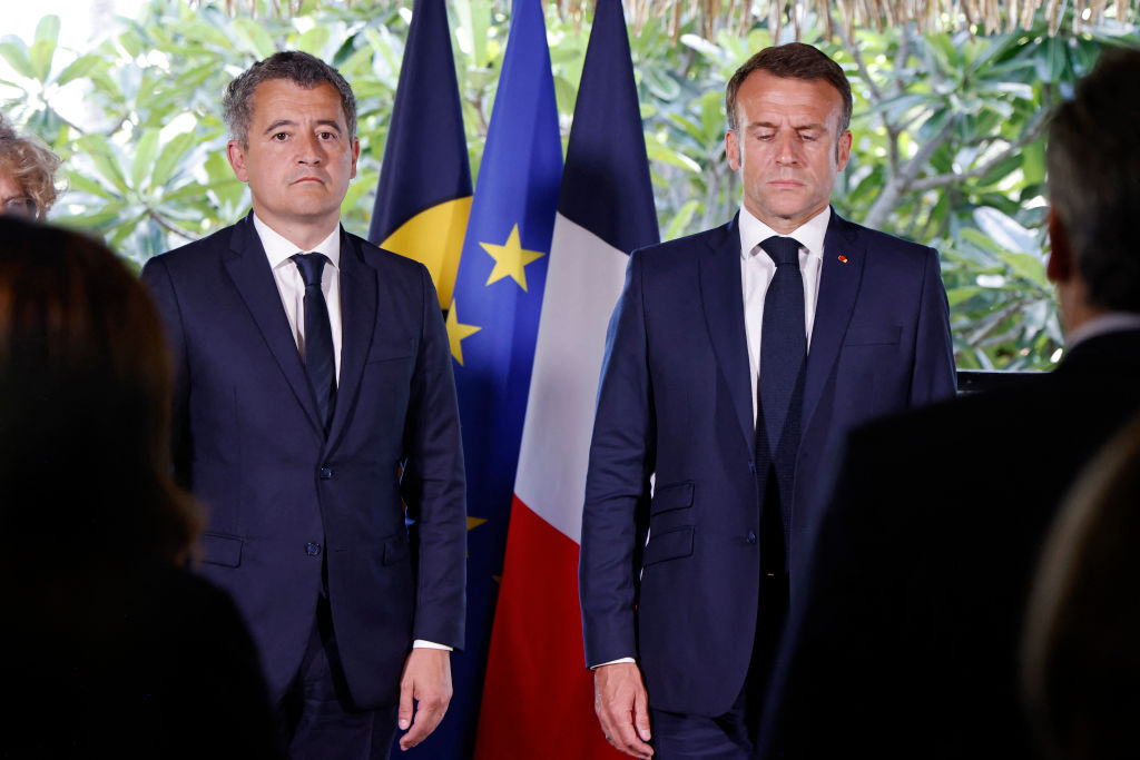 French President Emmanuel Macron, right, flanked by France's Minister for Interior and Overseas  Gérald Darmanin, stand for a minute of silence for the victims of deadly clashes in New Caledonia following a  meeting with officials and local representatives at the French High Commissioner's residence in Noumea (Ludovic Marin via AFP/Getty Images)