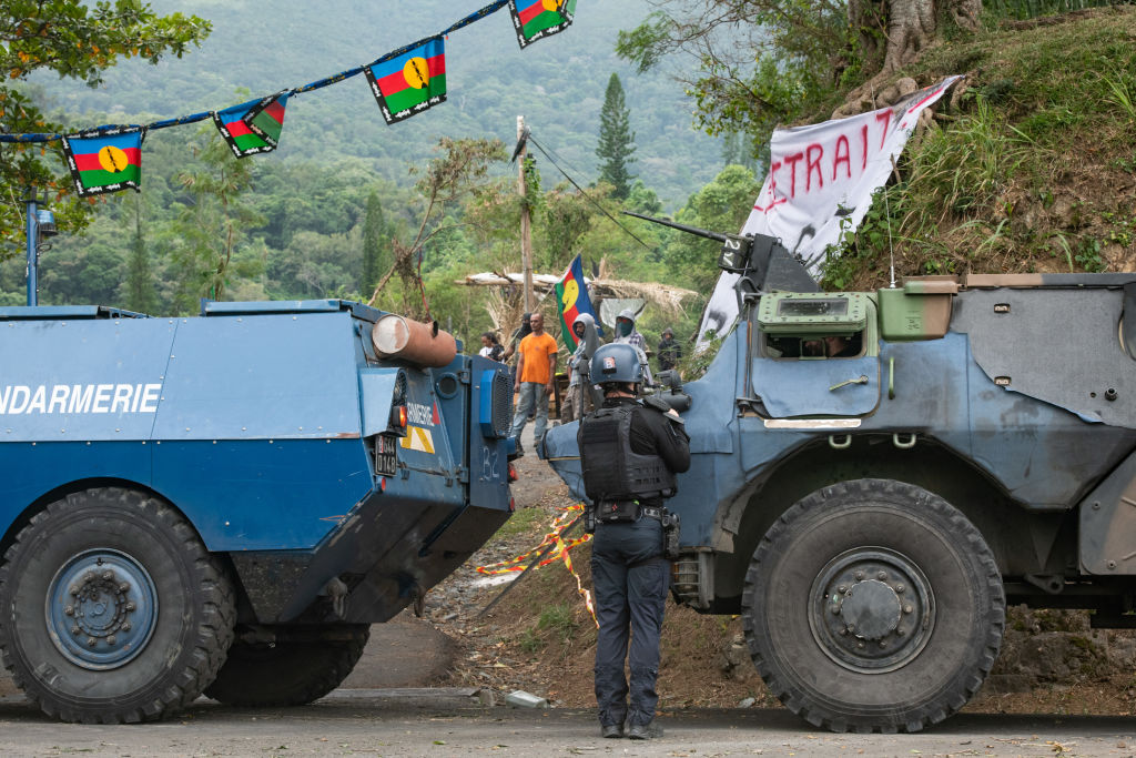 A French gendarme facing activists as a convoy of vehicles clear roadblocks in New Caledonia (Delphine Mayeur/AFP via Getty Images)
